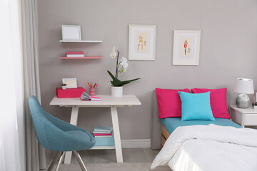 Modern teenager's room interior with comfortable bed and workplace