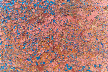 Peeling old paint on the wall. Concrete wall. Weathered rough painted surface with patterns of cracks and delamination.