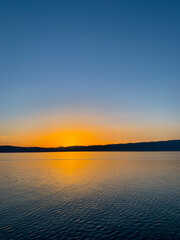 Idyllic orange sunset at the lake, silhouette of the mountains background
