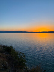 Idyllic orange sunset at the lake, silhouette of the mountains background