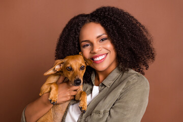 Portrait of adorable girl holding hands pup toothy smile look camera have good mood isolated on brown color background
