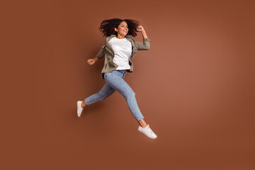 Fototapeta na wymiar Full size profile photo of funky millennial brunette lady run wear shirt jeans shoes isolated on brown background