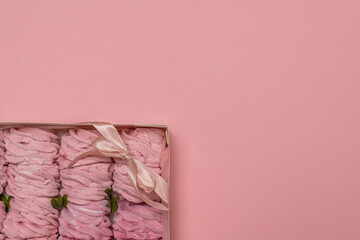 box with marshmallows. pink background. place for text. pink marshmallows