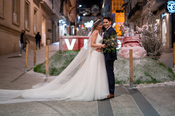 Fototapeta premium Couple on their wedding apparel against christmas street decoration