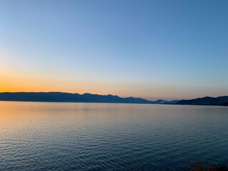 Idyllic orange sunset at the lake, silhouette of the mountains background