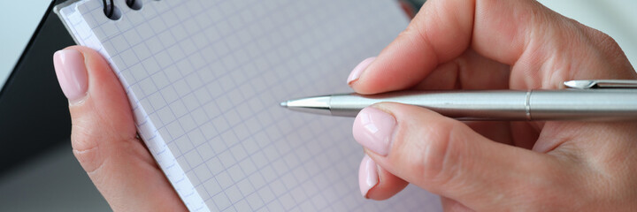 Woman hand holds pen and notebook closeup