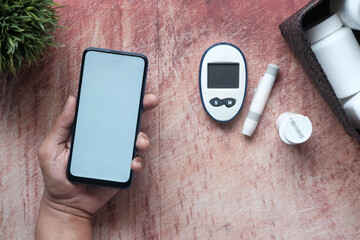  holding a smart phone and diabetic measurement tools on table 