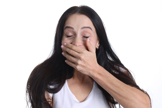 Portrait of woman covering hand over mouth on white background