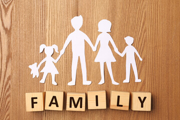 Paper cutout and word Family made of wooden cubes with letters on table, flat lay