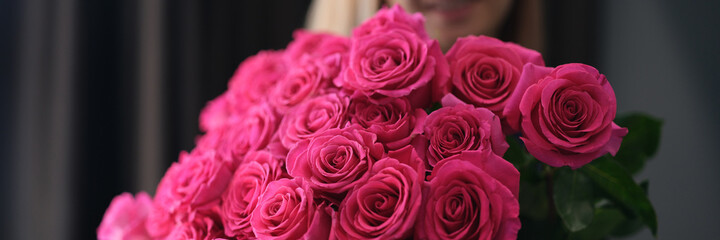 Smiling woman holding large bouquet of roses in her hands