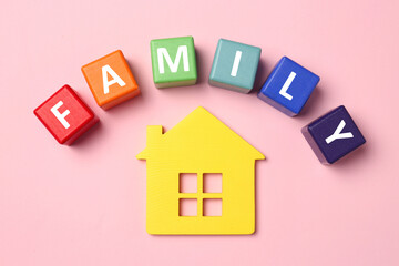 Fototapeta na wymiar House figure and word Family made of colorful cubes with letters on pink table, flat lay