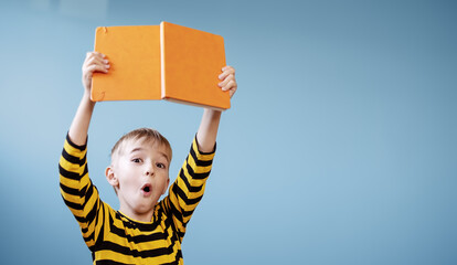 Surprised boy holding in his hands an interesting book