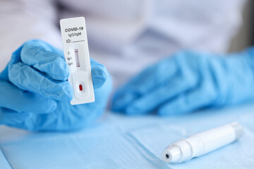 Doctor wearing disposable gloves holds positive PCR test for coronavirus infection