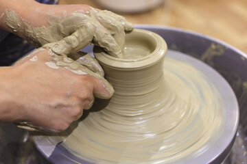 Female pottery artist shapes the clay on pottery wheel. Creative handmade craft. Closeup view