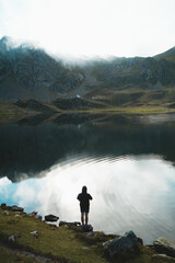 Guy wearing a hoodie taking a photo with his smart phone in Ayous Lake, Pyrenees