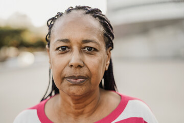 Senior african woman looking at camera outdoor in the city - Focus on face - Powered by Adobe