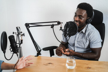 Hosts having podcast session together - African speaker making an interview during live stream -...