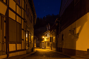 Altstadt von Stolberg im Harz bei Nacht. Von Straßenlaternen angestrahlte Fachwerkhäuser leuchten in der Dunkelheit.