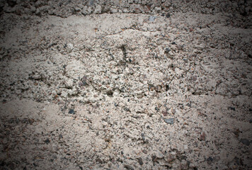The old cinder-concrete wall is gray with damage and stones. Grey background with texture and vignette.