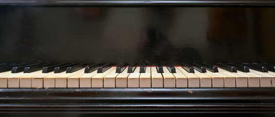 Old black grand piano keyboard with keys from ivory and ebony, part of a musical instrument in...