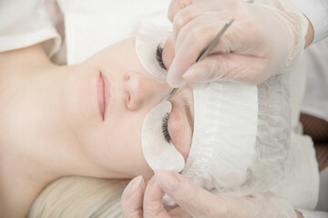 Eyelash extension procedure at  beauty salon. Woman eye with long eyelashes. Top down view