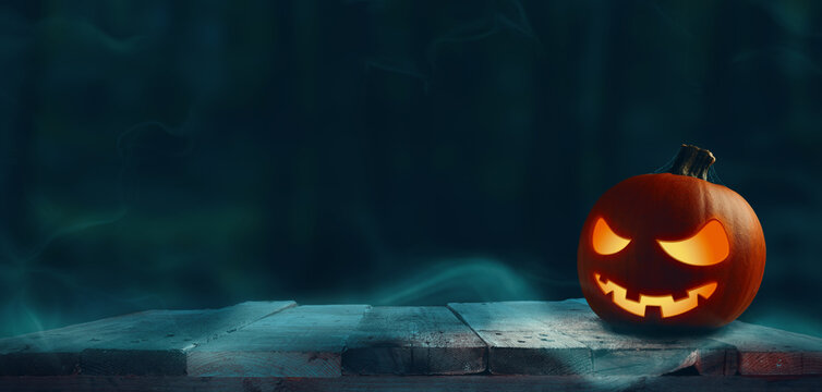 Carved halloween pumpkin Jack o lantern on a rustic wooden plank, dark forest, seasonal concept