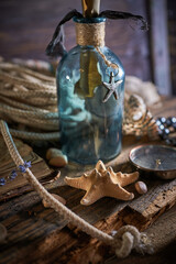 A marine concept with a bottle, starfish, seashells, rope, compass and paper scroll, pirate still life