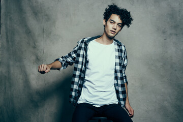 cute guy in a plaid shirt sitting on a chair posing studio