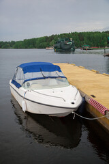 A white boat with a blue awning moored at the pier.