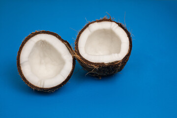 Fototapeta na wymiar halves of fresh coconut on a blue background.