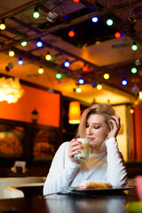 Beautiful woman drinking coffee at the cafe wintertime.