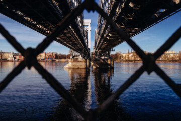 Closeup of a bridge over the river through a rusty cyclone fence