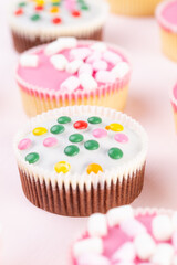 Colorful cupcakes on a pink background.