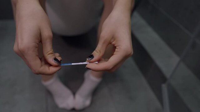 Woman sitting on the toilet twiddling with a piece of string