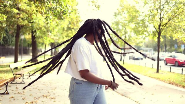 Young Woman Dancing and Tossing Hair Outdoors
