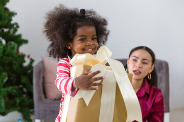 African American mother and little girl and little son playing with Christmas gift box or presents gift at home. Merry Christmas and Happy Holidays. Happy family on Christmas