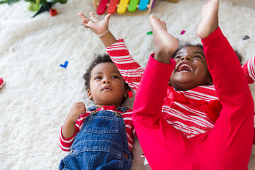 Cheerful cute African American little smiling girl and little boy having fun on floor at home. Christmas holiday celebration, Merry Christmas and Happy Holidays