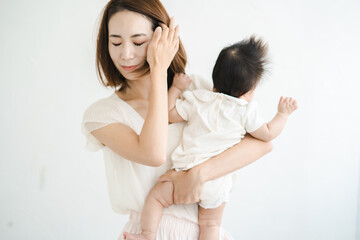 赤ちゃんを抱えて、疲れた表情をするお母さん