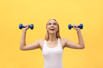 Fototapeta na wymiar Fitness woman lifting weights smiling happy isolated on yellow background. Fit sporty Caucasian female fitness model.