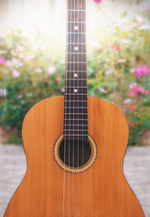 Obraz premium Yellow traditional soprano ukulele guitar on a background of greenery and flowers. Guitar on a summer background. The concept of music.