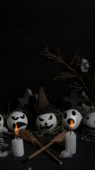 HALLOWEEN, GOLF BALLS DECORATED LIKE PUMPKINS WITH TERRORIFIC FACES WITH CANDLES, FOLIAGE, CROSSES, INSECTS ON RUSTIC WOODEN TABLE AND DARK BACKGROUND WITH SPACE FOR TEXT