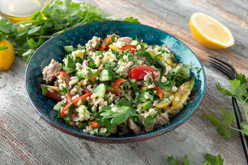 bowl of Lebanese tabbouleh salad with vegetables, bulgur and canned tuna on a wooden table