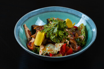 Salad with meat and vegetables on a black background