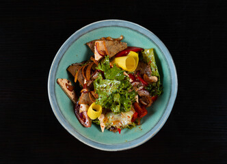 Salad with meat and vegetables on a black background