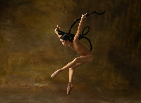 Full-length art portrait of beautiful ballerina dancing isolated over vintage background.