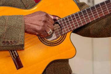 Image of a guitar player, without identifying the face, highlighting his hand, which is old, and is...