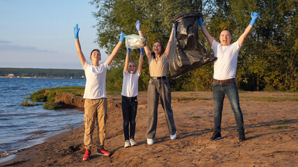 family of four with teenagers clearing the beach from plastic debris. Collaboration. Environmental...