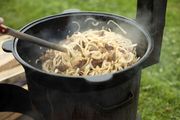 Cooking pilaf. The food is fried in a frying pan. Lunch in nature.