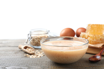 Homemade hair mask in bowl and fresh ingredients on wooden table against white background. Space for text