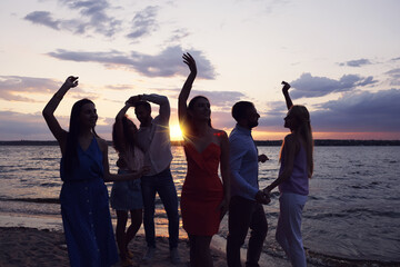 Fototapeta premium Group of friends having fun near river at sunset. Summer party